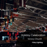 Indoor church hall decorated with string lights and international flags for a holiday celebration at Victory Church.